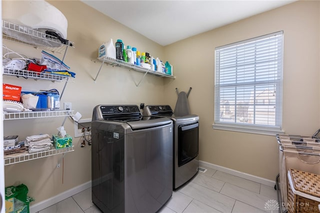 laundry room featuring washing machine and dryer, plenty of natural light, and light tile patterned floors