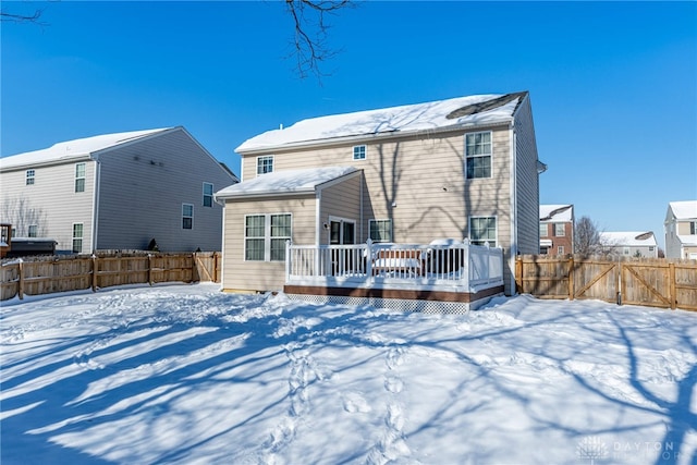 snow covered rear of property with a wooden deck