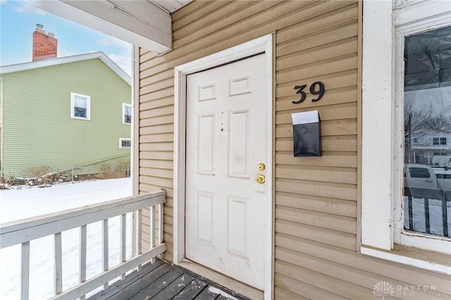 snow covered property entrance with covered porch