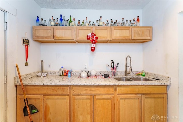 kitchen with light stone countertops, sink, and a textured ceiling