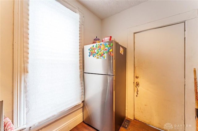 kitchen featuring stainless steel fridge, wood-type flooring, and a textured ceiling