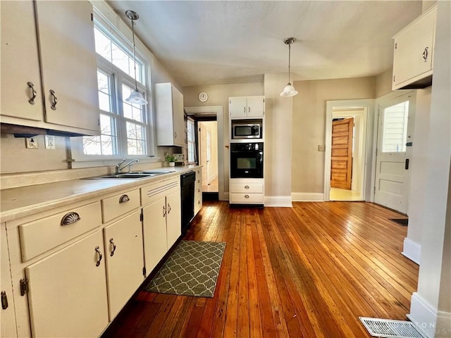 kitchen featuring black appliances, sink, hanging light fixtures, white cabinets, and dark hardwood / wood-style flooring