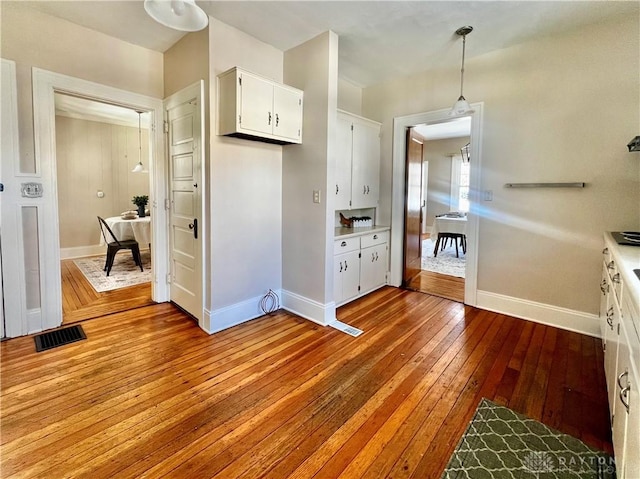 kitchen with hanging light fixtures, white cabinets, and light hardwood / wood-style flooring