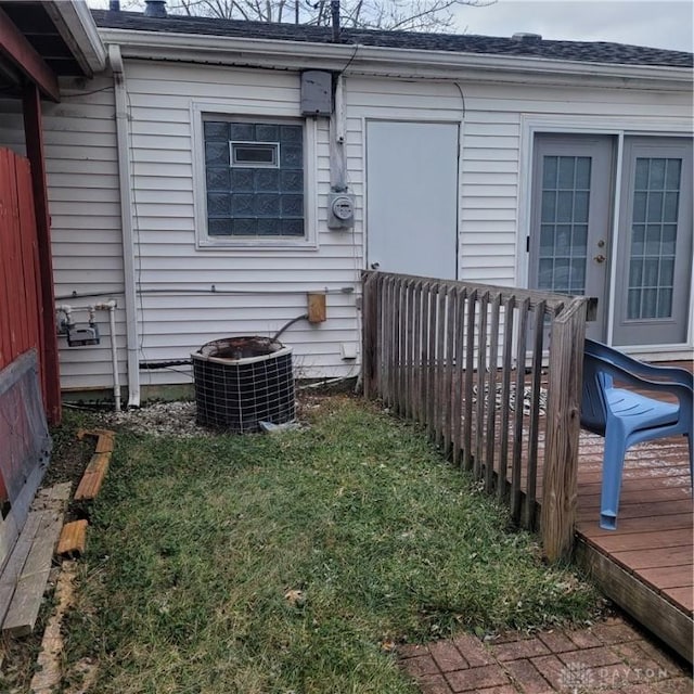 doorway to property featuring a deck, central AC unit, and a lawn