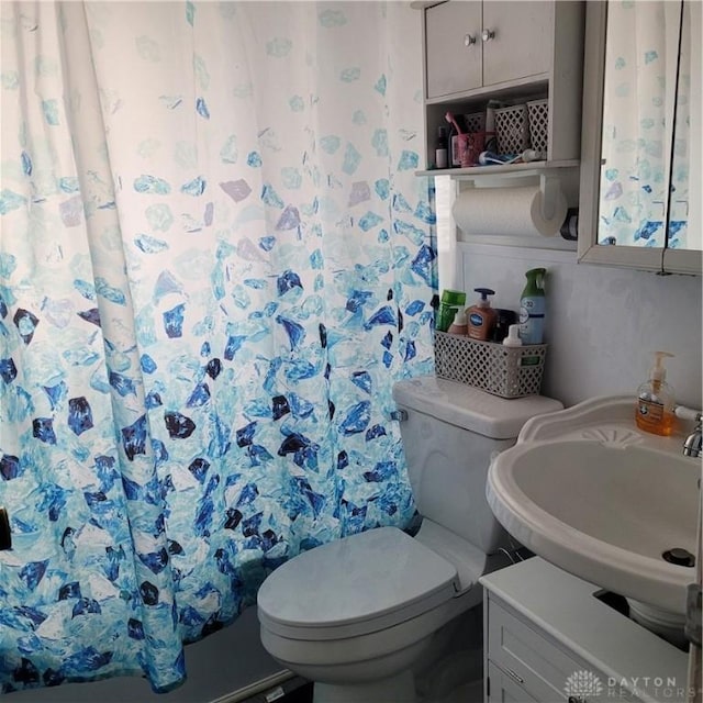 bathroom featuring a shower with shower curtain, toilet, and sink