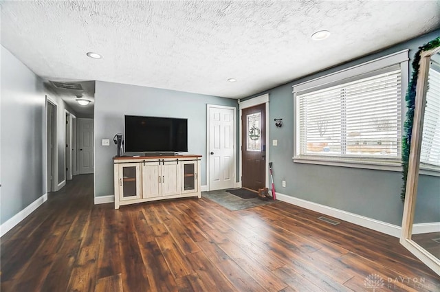 unfurnished living room featuring a textured ceiling and dark wood-type flooring