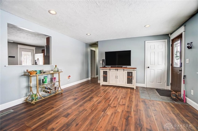 unfurnished living room with dark wood-type flooring and a textured ceiling