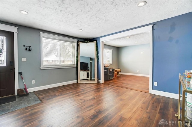 unfurnished living room featuring dark hardwood / wood-style flooring, a textured ceiling, and a wealth of natural light