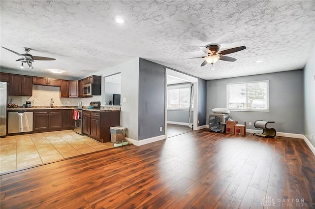 kitchen with ceiling fan, stainless steel appliances, a textured ceiling, and light hardwood / wood-style floors