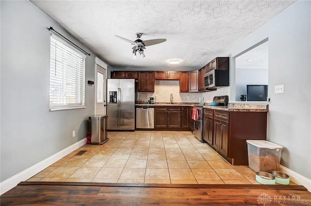 kitchen featuring ceiling fan, sink, a textured ceiling, light tile patterned floors, and appliances with stainless steel finishes