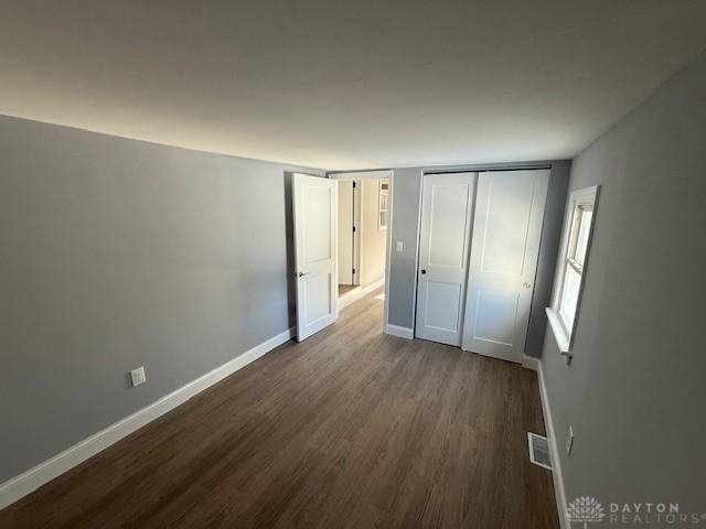 unfurnished bedroom featuring dark wood-type flooring and a closet