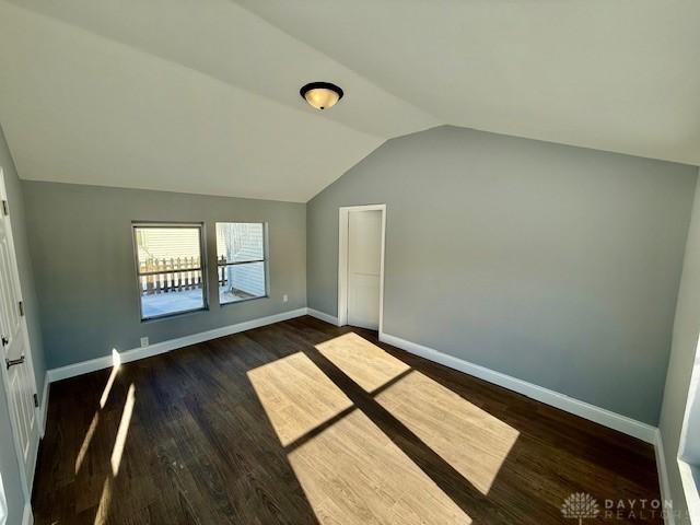 unfurnished bedroom featuring lofted ceiling and dark hardwood / wood-style flooring