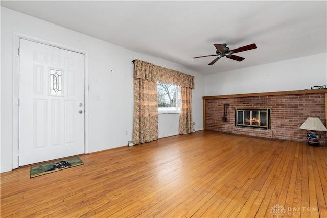 unfurnished living room with light hardwood / wood-style flooring, a brick fireplace, and ceiling fan