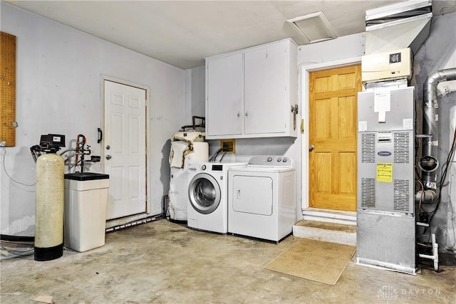 laundry room featuring washing machine and clothes dryer, heating unit, and cabinets