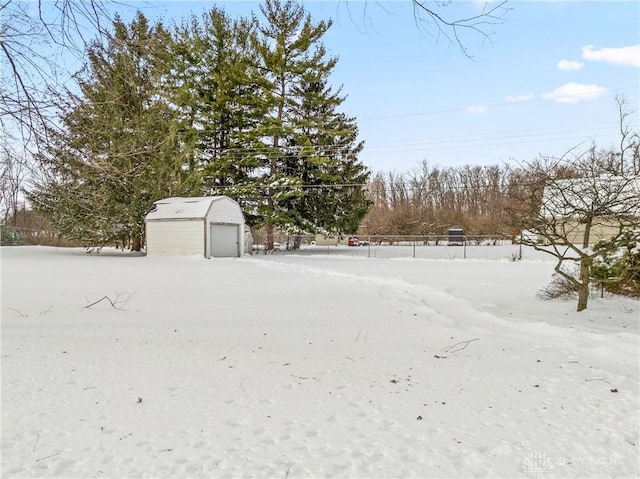 yard covered in snow featuring a garage and an outdoor structure