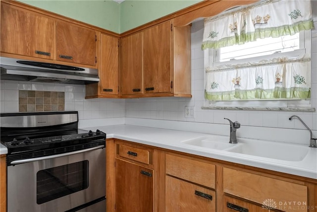 kitchen featuring stainless steel electric range, decorative backsplash, and sink