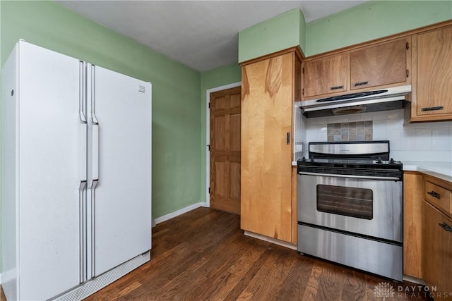 kitchen featuring gas range, backsplash, white fridge, and dark hardwood / wood-style floors