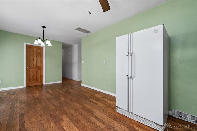 spare room featuring ceiling fan with notable chandelier and dark hardwood / wood-style floors