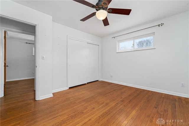 unfurnished bedroom with ceiling fan, a closet, and wood-type flooring