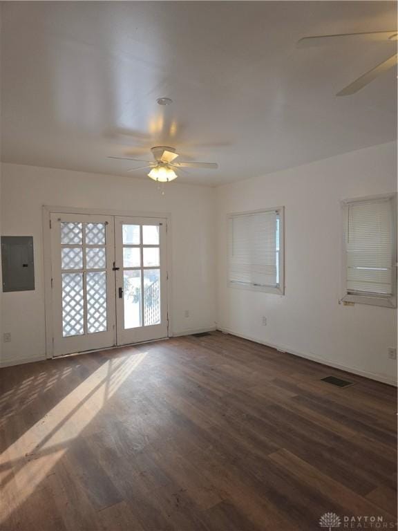 spare room with dark wood-type flooring, ceiling fan, and electric panel