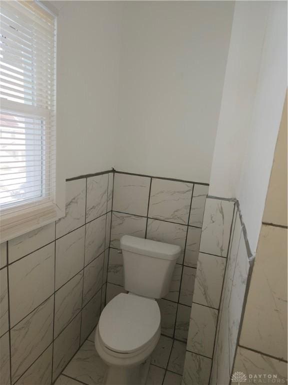 bathroom with tile walls and toilet