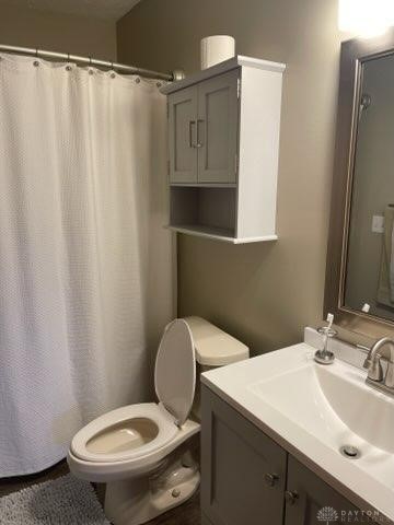 bathroom featuring vanity, curtained shower, and toilet