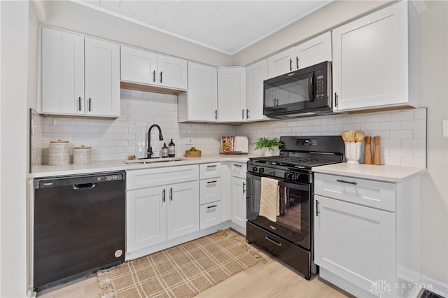 kitchen with white cabinetry, sink, decorative backsplash, and black appliances