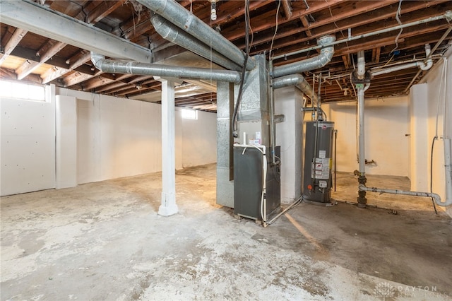 basement featuring heating unit, a healthy amount of sunlight, and water heater