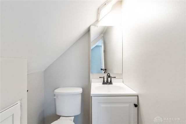 bathroom featuring lofted ceiling, vanity, and toilet