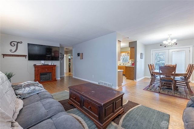 living room with light hardwood / wood-style flooring, french doors, and a notable chandelier