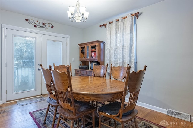 dining space with dark wood-type flooring and an inviting chandelier