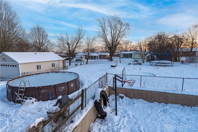 yard layered in snow featuring a trampoline