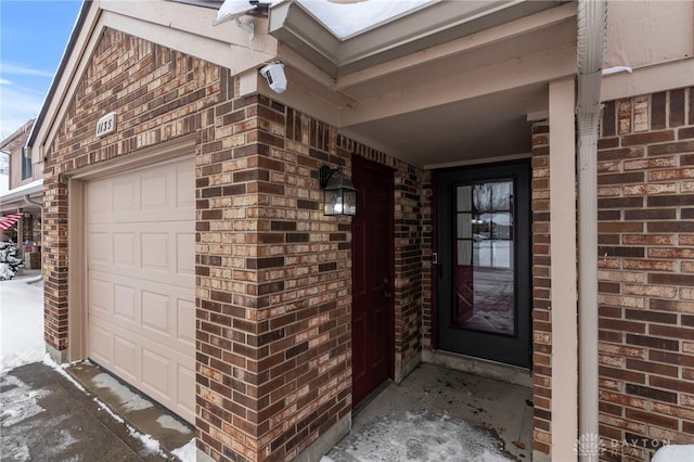 snow covered property entrance with a garage