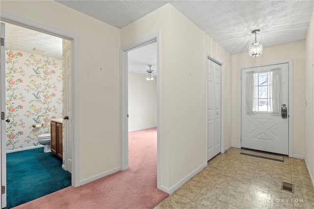 carpeted entrance foyer featuring a textured ceiling and ceiling fan