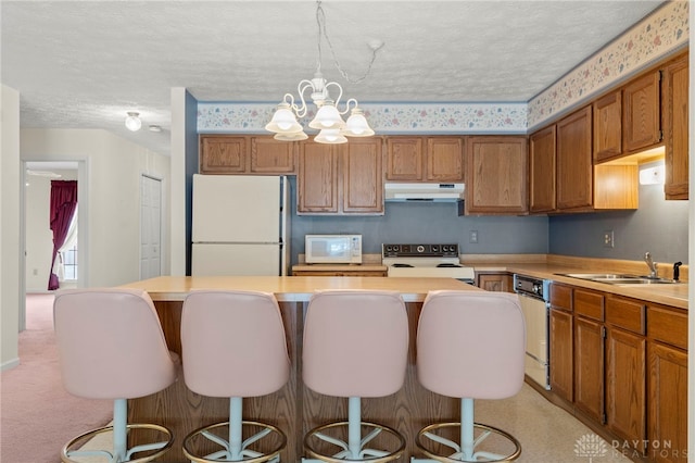 kitchen with a center island, white appliances, a textured ceiling, and an inviting chandelier