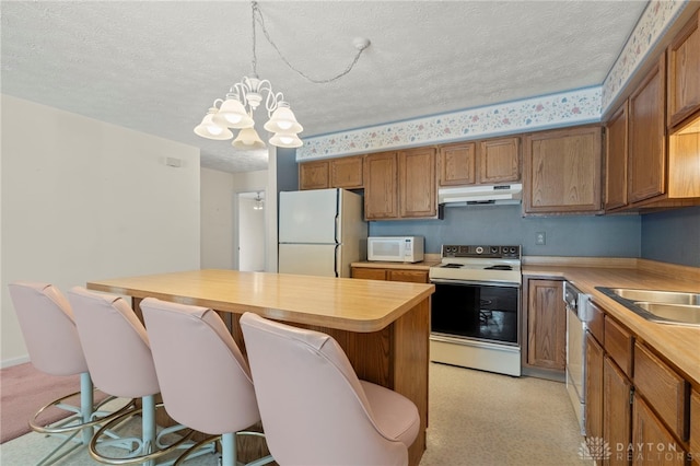 kitchen with decorative light fixtures, white appliances, a textured ceiling, and a chandelier