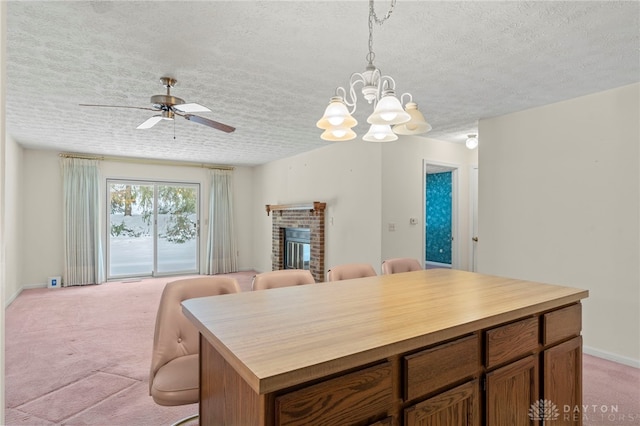 kitchen featuring light carpet, a textured ceiling, ceiling fan with notable chandelier, decorative light fixtures, and a fireplace