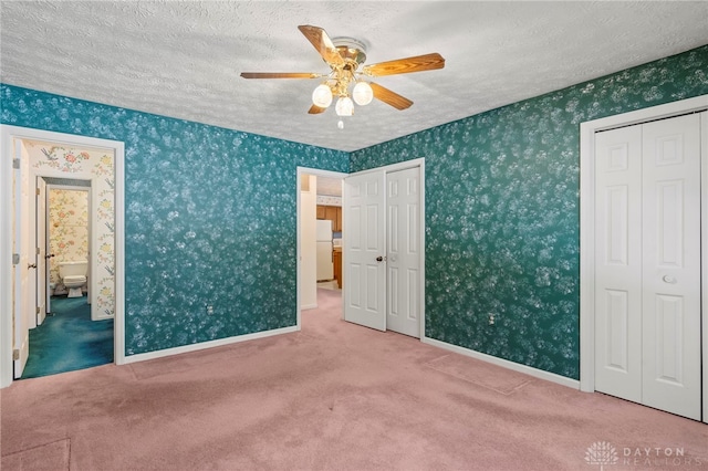 unfurnished bedroom with a textured ceiling, white refrigerator, carpet floors, and ceiling fan