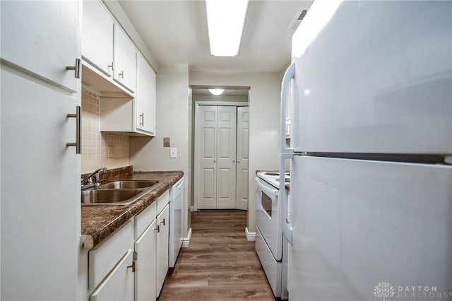 kitchen with white cabinetry, sink, wood-type flooring, white appliances, and decorative backsplash