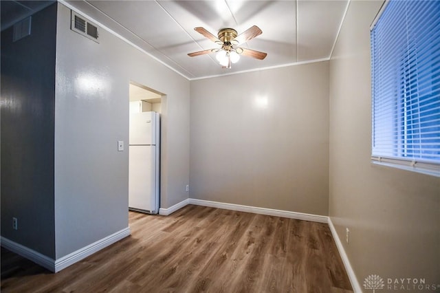 empty room featuring ceiling fan, crown molding, and wood-type flooring