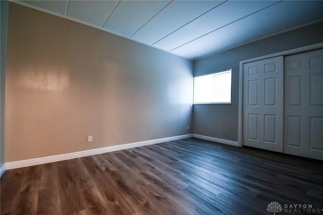 unfurnished bedroom with dark hardwood / wood-style flooring and a closet