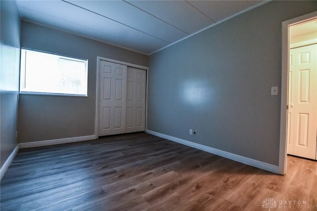 unfurnished bedroom with dark hardwood / wood-style flooring and a closet