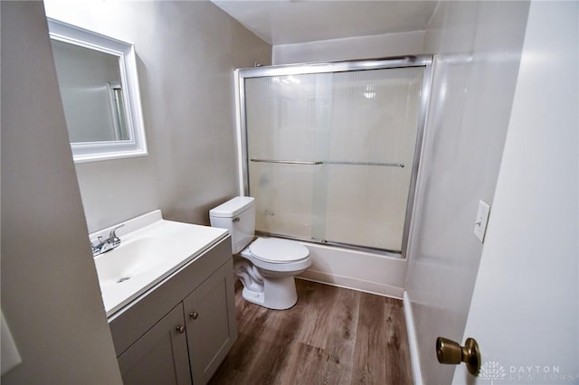 full bathroom with hardwood / wood-style floors, vanity, toilet, and bath / shower combo with glass door