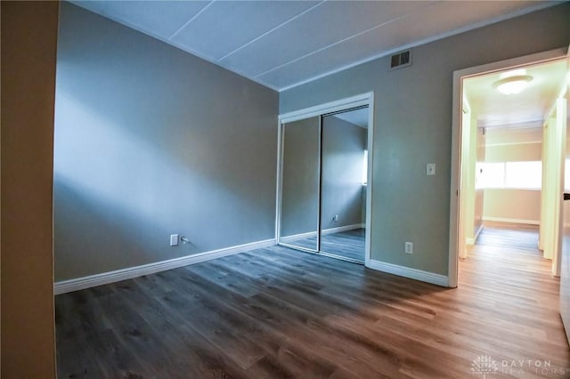 unfurnished bedroom with dark hardwood / wood-style floors and a closet