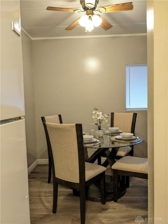 dining area featuring wood-type flooring, ceiling fan, and crown molding