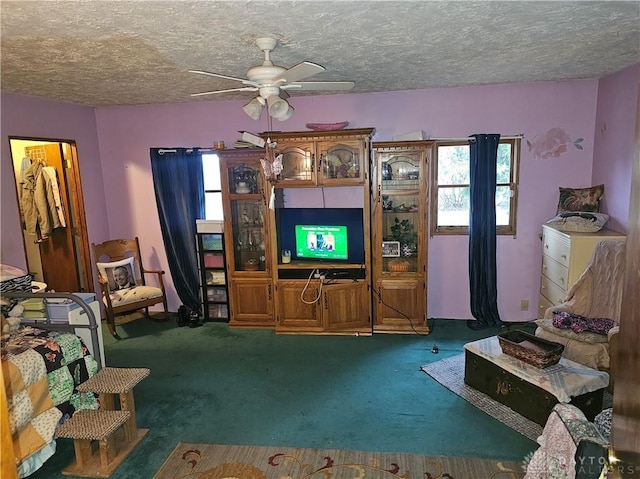 carpeted living room featuring ceiling fan and a textured ceiling