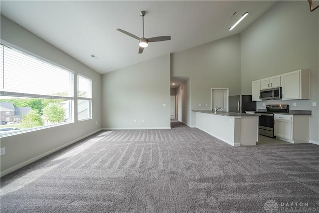 unfurnished living room with ceiling fan, carpet floors, sink, and high vaulted ceiling