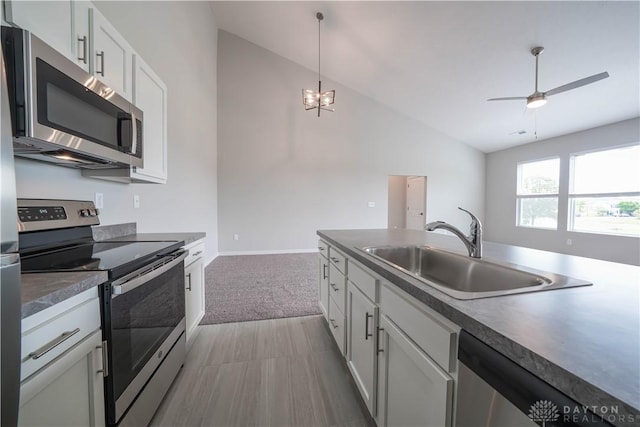 kitchen with stainless steel appliances, sink, white cabinetry, hanging light fixtures, and lofted ceiling