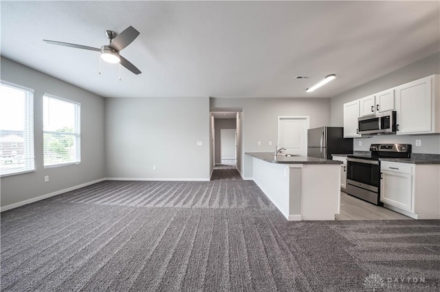 kitchen with light carpet, appliances with stainless steel finishes, ceiling fan, sink, and white cabinets