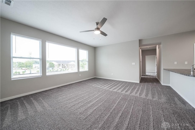 unfurnished living room with dark colored carpet and ceiling fan